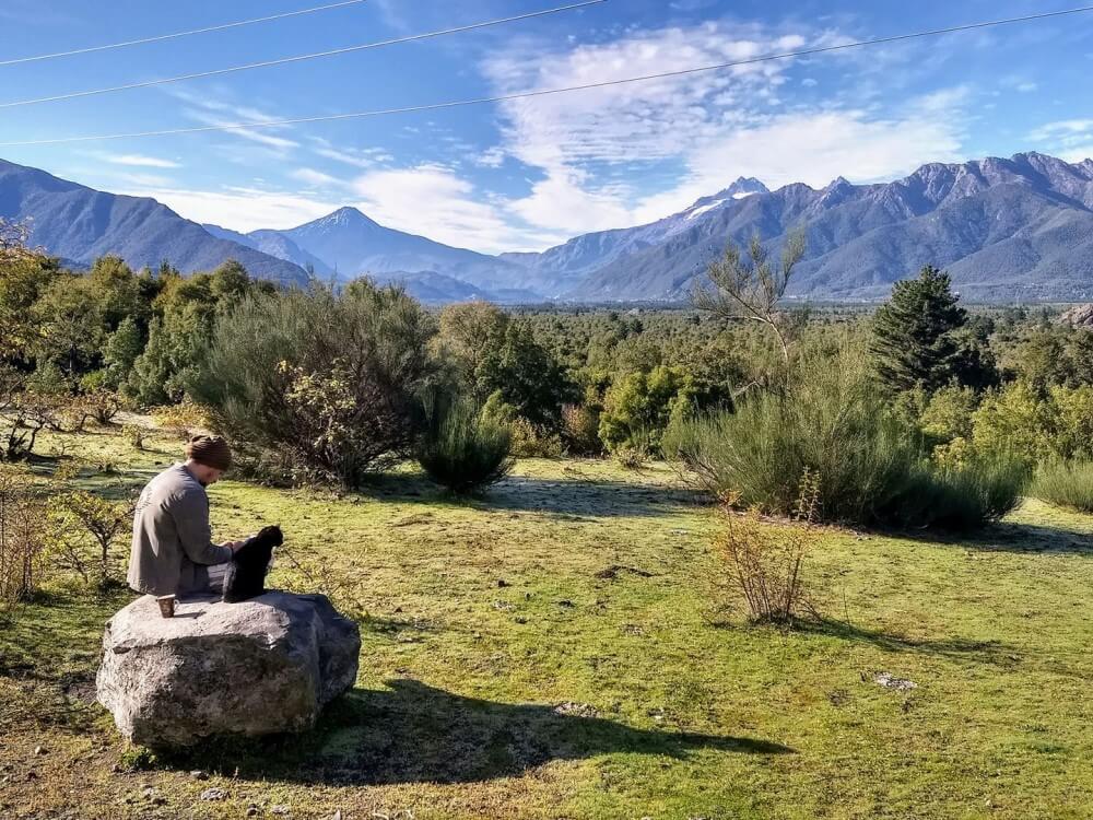 A man sitting on a rock near a mountain range